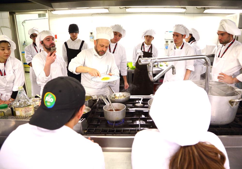 Culinary students attentively watching their chef demonstrate cooking techniques.