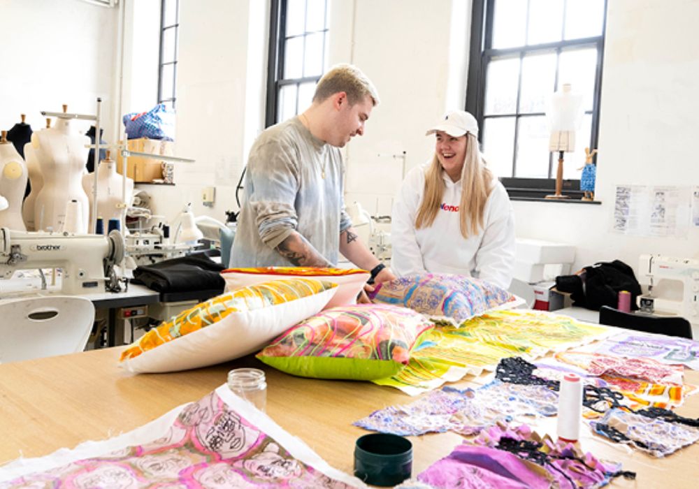 Two people surrounded by fabric and tools in a organized sewing room.