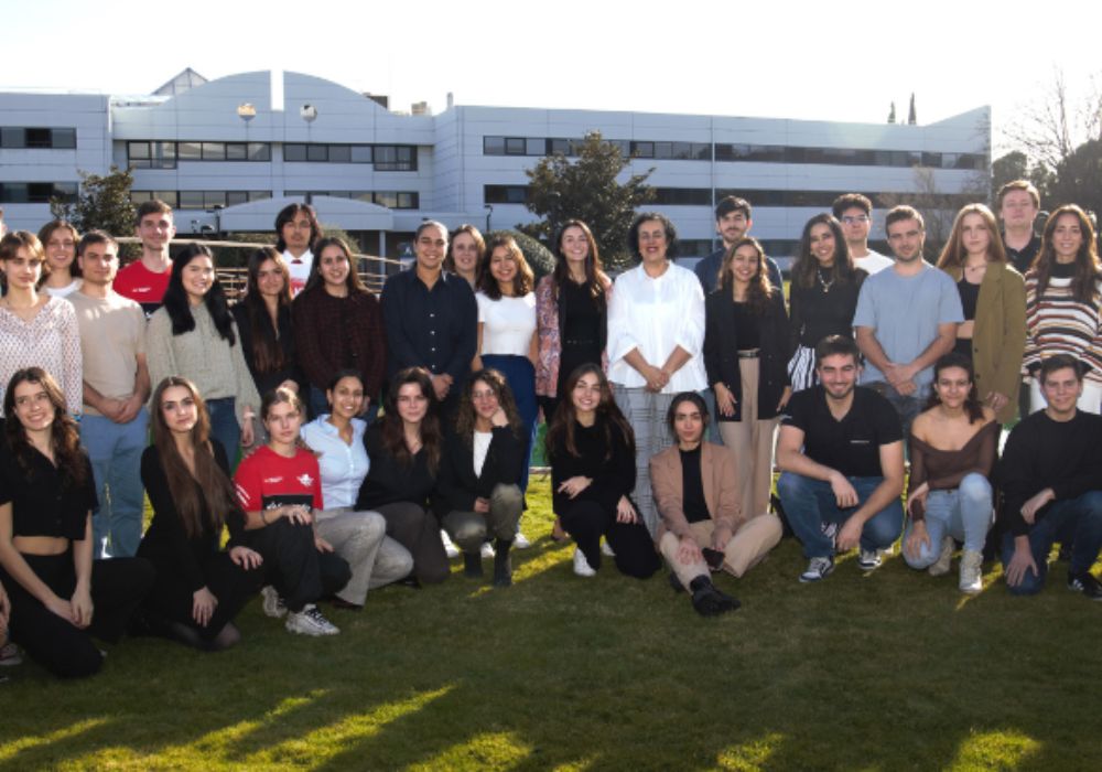 A group of young individuals smiling and posing together in front of a building.