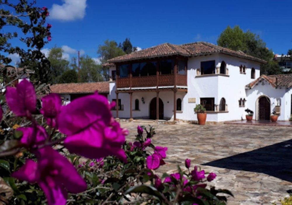 A white building surrounded by purple flowers in the foreground.